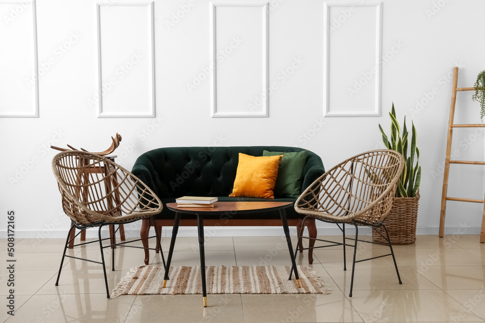Stylish sofa and armchairs near light wall