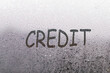 the word credit written on night wet window glass close-up with blurred background