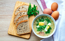 One Bowl Of Żurek Soup Is A Festive Traditional Polish Soup. Delicious Hot Soup With Egg And Sausage, Bread And Fresh Herbs On The Table. Horizontal Photo.