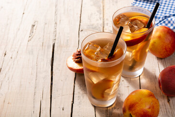 Poster - Glass of peach tea with ice cubes on wooden table. Copy space