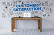 Schriftzug Customer Satisfaction über Schreibtisch