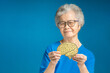 Portrait of a senior woman holding a brain mockup and looking at the camera while standing on a blue background