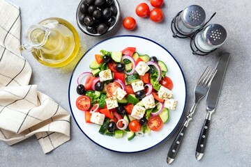 Wall Mural - Greek salad with feta cheese and black olives on plate, table top view. Healthy summer food