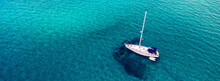 Aerial View Of Anchored Sailing Yacht In Emerald Sea. Aerial View Of A Boat. Outdoor Water Sports, Yachting. Aerial View Of Anchoring Yacht In Open Water. Ocean And Sea Travel And Transportation