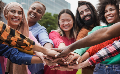 Group of young multiethnic people stacking hands in the city