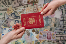 Two Hands Holding Russian Passport On Different Currencies Background