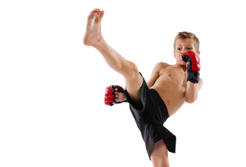 Beginner athlete, kid in sports shots and gloves practicing thai boxing on white studio background. Sport, education, action, motion concept.