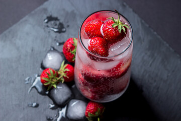 Wall Mural - Cocktail with strawberries and ice on a black background. Refreshing drink.