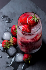 Wall Mural - Cocktail with strawberries and ice on a black background. Refreshing drink.