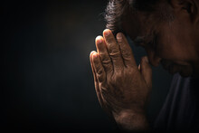 Elderly Asian Man Bowed His Head Praying To God On A Black Background At Home. Holding Hands In Prayer, Eyes Closed.