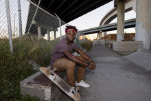 Portrait Of Black Man With Skateboard Under Flyover
