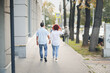Cute European middle-aged couple holding hands walking in the city street, man and woman walking down the street in summer, back view