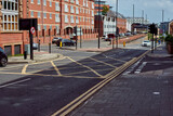 Fototapeta Sawanna - Crossroads with a yellow waffle iron. Road markings in England. Beautiful street with black asphalt.