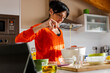 © Cavan Images - Woman in orange sweater whisking eggs on a white bowl.