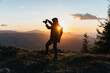 © Cavan Images - Silhouette of Man Holding Camera at Sunset on the Mountain