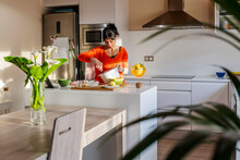 Woman In Orange Sweater Whisking Eggs On A White Bowl.