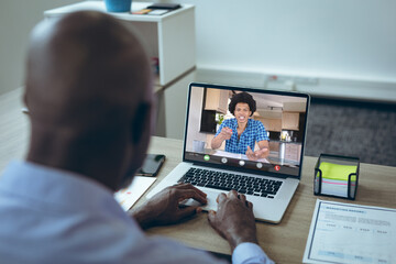 Sticker - African american young male colleagues talking during video conference on laptop at desk in office