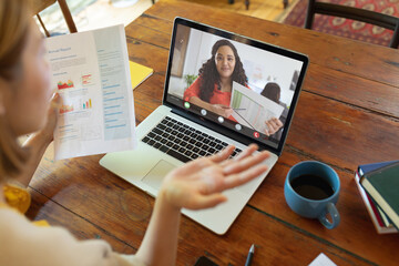 Wall Mural - Caucasian young businesswoman gesturing during online meeting with biracial young female colleague