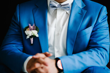 Wall Mural - Wedding. The groom in a shirt, bow-tie and a suit with a buttonhole on black wall background. Rich man at wedding day. Close up.