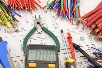 Multimeter and mounting tools in the electrical diagram close-up.