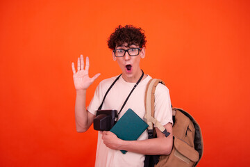 Wall Mural - Young attractive tourist with a backpack. Orange background.