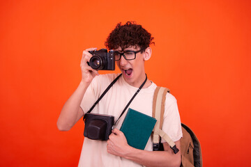 Wall Mural - Young attractive tourist with a backpack. Orange background.