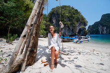Relax Vacation. Young Woman Swinging On Teeterboard Near The Sea With Fisshing Longtail Boats In Thailand.