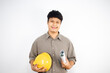 © Rurgrit - An Asian male engineer holding a safety helmet and blueprint looks at the camera and smiles on white background