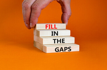 Fill in the gaps symbol. Concept words Fill in the gaps on wooden blocks on a beautiful orange table orange background. Businessman hand. Business, motivational and fill in the gaps concept.