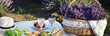Wicker basket, tasty food and drink for romantic picnic in lavender field
