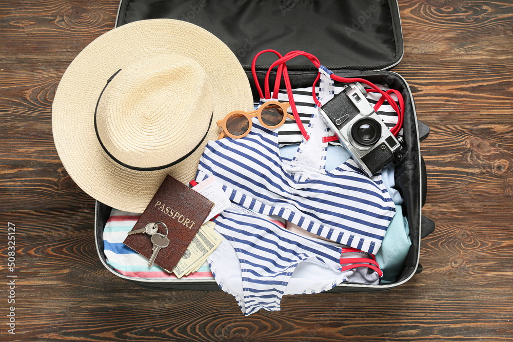 Suitcase with guide's belongings on wooden background