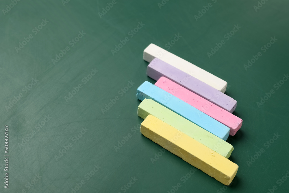 Colorful chalks on green blackboard