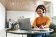 © Prostock-studio - Woman sitting at desk, using computer and writing in notebook