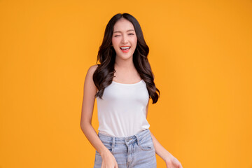 casual happiness asian female woman smiling cheerful in white tshirt blue jean relax peaceful positive thinking carefree lifestyle standing with yellow color background studio shoot