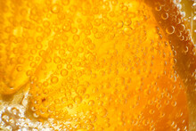 Closeup Full Frame Of Round Orange Slice In Glass With Transparent Refreshing Alcoholic Gin And Tonic Cocktail With Small Bubbles
