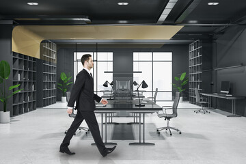 Poster - Attractive thoughtful young european business person walking in wooden and concrete office interior with furnituire and window with city view. CEO, executive and consulting concept.