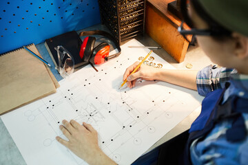 Wall Mural - Above view of busy engineer standing at table and drawing on sketch while designing house plan