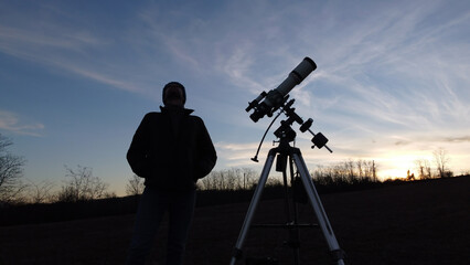 Wall Mural - silhouette of a man, telescope and countryside under evening skies.