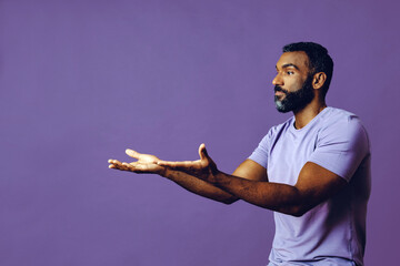 Wall Mural - young black man with beard and mustache smiling and looking away at copy space hand signal isolated blue background studio