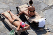 © Oleg - Two girls sunbathing on lounge chairs, top view. Girlfriends in bikini using smartphones on a beach, holiday and vacation