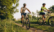 © sergo321 - A man and a woman ride bicycles on a dirt road in the summer at sunset. Active rest in the summer on bicycles.