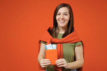 Wall Mural - Traveler tourist woman wear khaki t-shirt sweatshirt hold passport boarding tickets isolated on plain orange background studio. Passenger travel abroad on weekends getaway. Air flight journey concept.