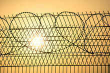 Barbed Wire Wall Against The Backdrop Of The Setting Sun. Metaphor Of Slavery And The Search For Freedom