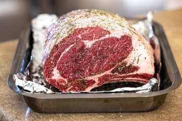 Raw prime rib roast seasoned and sitting on an aluminum foil lined pan ready for the oven for a holiday Christmas dinner