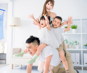 Wall Mural - Father giving piggyback to excited child and playing at home