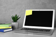 © New Africa - Laptop with empty sticky note and stationery on white table near grey wall. Space for text