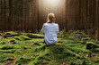 ©  sailka - Woman sitting in green forest enjoys the silence and beauty of nature.