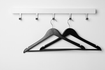 Rack with empty black clothes hanger on white wall