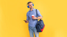 Handsome Businessman In Headphones Use Smartphone With Travel Bag. Man Listen Music