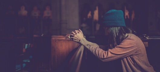 Young woman prayer's pray alone in church, People pray to God with folded hands, old wooden classic long chairs background